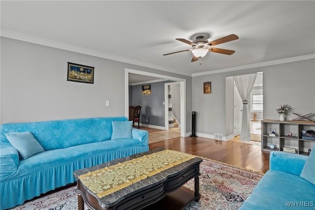 living area with a ceiling fan, wood finished floors, stairway, crown molding, and baseboards