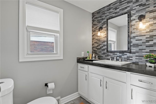 bathroom featuring toilet, tasteful backsplash, vanity, and baseboards