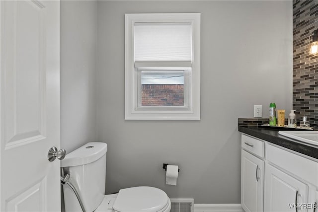 bathroom with toilet, tasteful backsplash, vanity, and baseboards