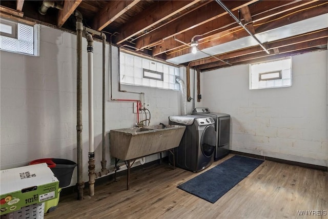 clothes washing area with washing machine and clothes dryer and wood finished floors