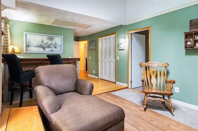 living room with attic access, baseboards, and wood finished floors