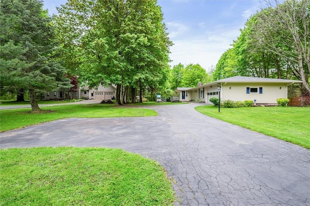 view of front of home with a front yard, a garage, asphalt driveway, and a chimney