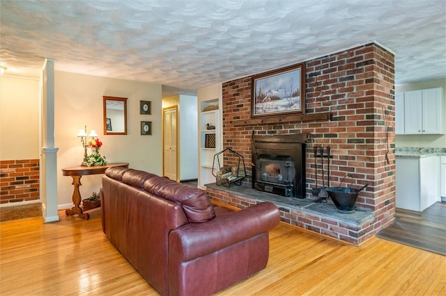 living room with a textured ceiling, baseboards, and light wood-style floors