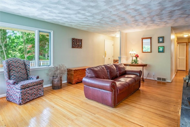 living area featuring a textured ceiling, light wood finished floors, and baseboards