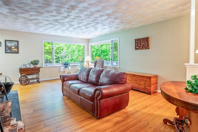 living area featuring light wood-style flooring, baseboards, and a textured ceiling