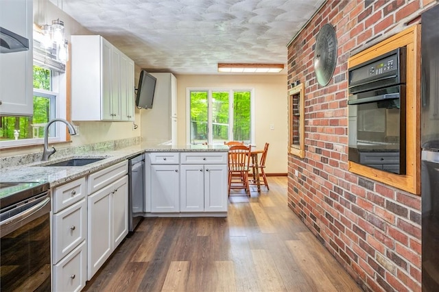 kitchen with stainless steel appliances, a sink, plenty of natural light, dark wood finished floors, and a textured ceiling