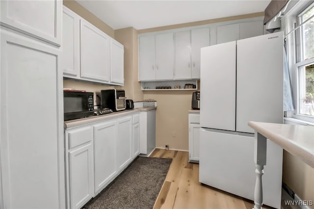 2254 Grand Ave, Niagara Falls, NY 14301 - kitchen with freestanding refrigerator, black microwave, healthy amount of natural light, and white cabinets