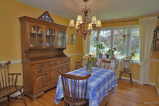 dining space with a chandelier, light wood-type flooring, and baseboards
