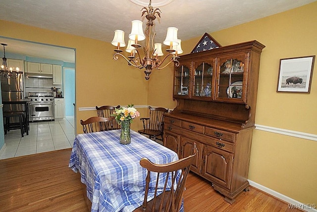 dining area featuring a chandelier, light wood finished floors, and baseboards