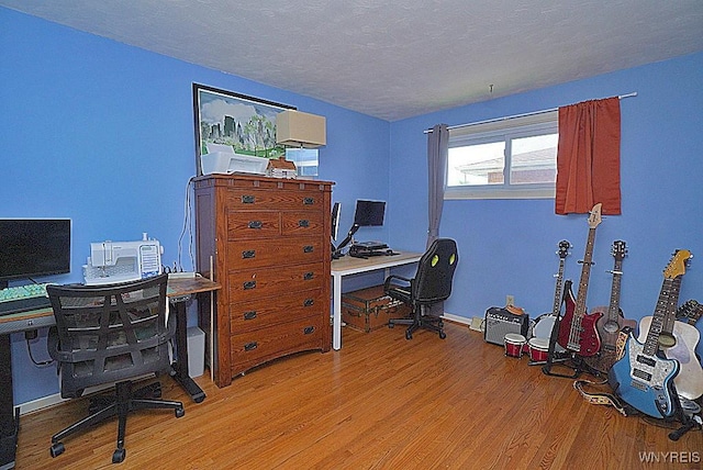 home office with wood finished floors, a textured ceiling, and baseboards
