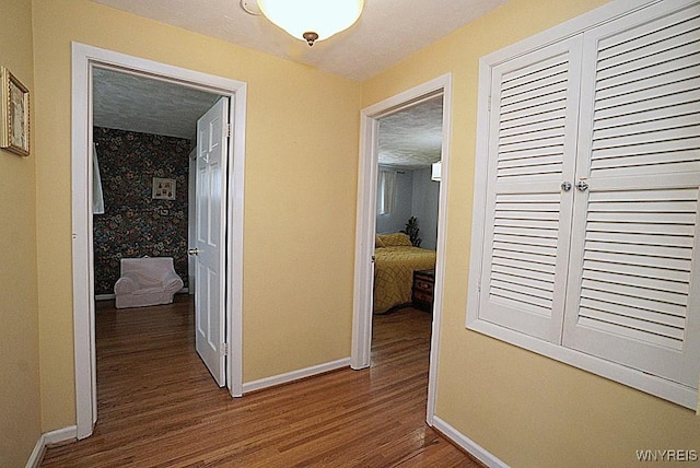 corridor with baseboards and wood finished floors