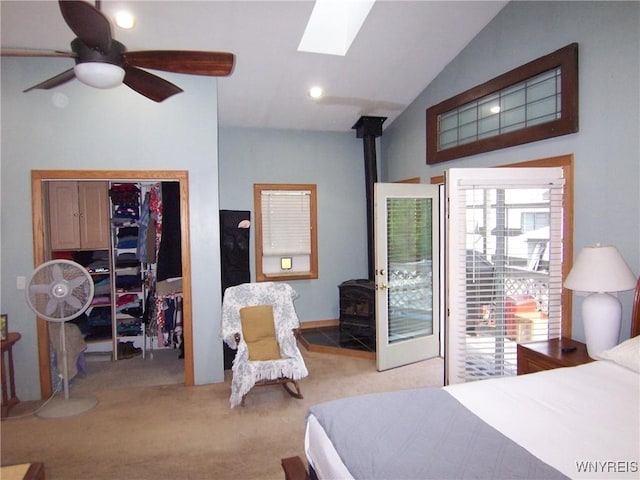 bedroom featuring a wood stove, carpet, lofted ceiling, a skylight, and a closet