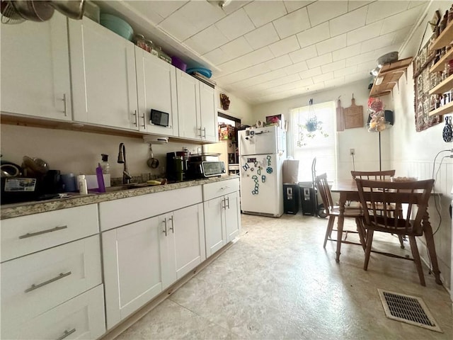 11 Gilbert St, Oneonta-City, NY 13820 - kitchen with freestanding refrigerator, a sink, and white cabinetry
