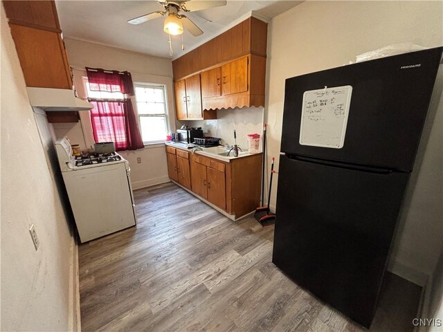 236 N Midler Ave, Syracuse, NY 13206 - kitchen featuring freestanding refrigerator, white gas range oven, light wood-style floors, under cabinet range hood, and brown cabinetry