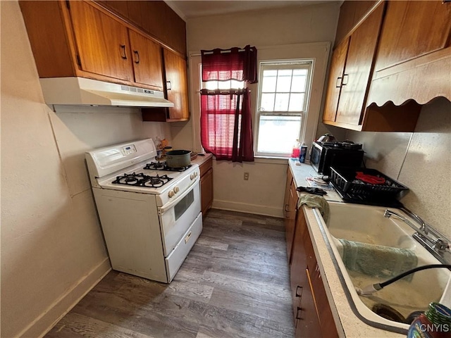 236 N Midler Ave, Syracuse, NY 13206 - kitchen with under cabinet range hood, white range with gas stovetop, dark wood finished floors, brown cabinetry, and baseboards