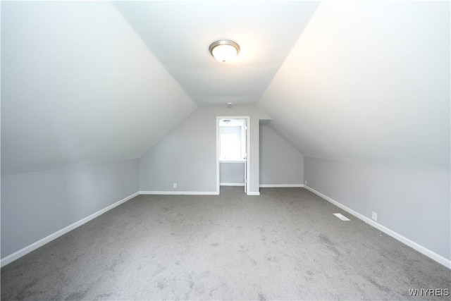 additional living space with carpet flooring, baseboards, and vaulted ceiling