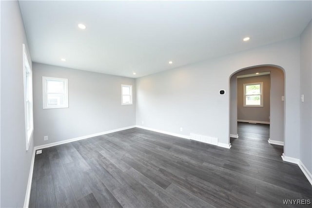 unfurnished room with arched walkways, dark wood-style flooring, baseboards, and recessed lighting