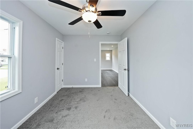 carpeted empty room with ceiling fan and baseboards