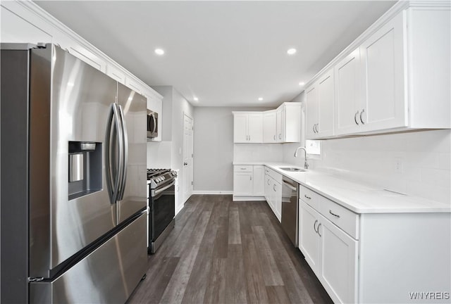 kitchen featuring appliances with stainless steel finishes, recessed lighting, a sink, dark wood-type flooring, and white cabinets