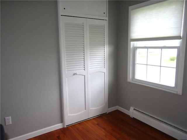 129 Daffodil Dr, Horseheads, NY 14845 - unfurnished bedroom featuring a baseboard radiator, a closet, baseboards, and dark wood-type flooring