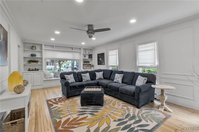 living area with light wood-style floors, built in shelves, ceiling fan, recessed lighting, and a decorative wall