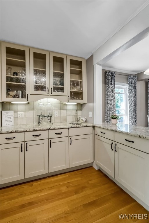 bar with tasteful backsplash, a sink, and light wood-style floors