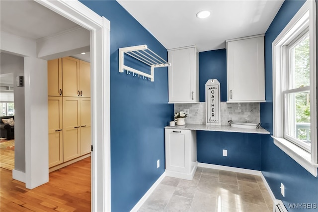 kitchen featuring baseboards, decorative backsplash, recessed lighting, and light stone counters
