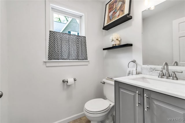 bathroom featuring toilet, vanity, and baseboards