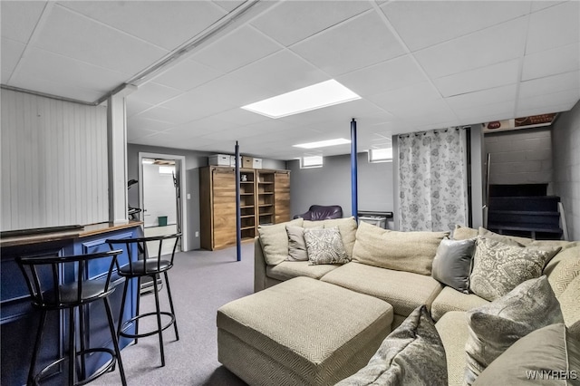 living area featuring carpet floors, a paneled ceiling, and a bar