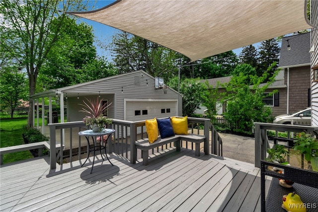 wooden deck with a detached garage and an outbuilding