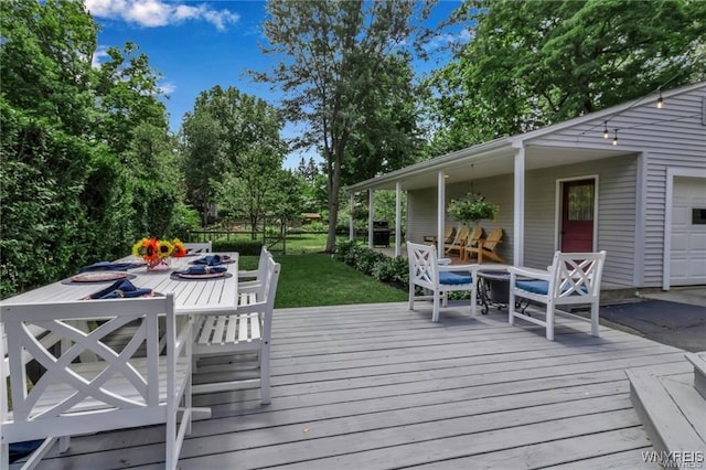wooden deck featuring outdoor dining space and a garage