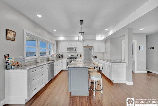 5518 Wells Bay Lakefront, North Harmony, NY 14710 - kitchen featuring appliances with stainless steel finishes, a sink, light wood-type flooring, a breakfast bar, and white cabinetry