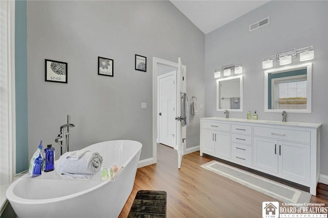 5518 Wells Bay Lakefront, North Harmony, NY 14710 - full bath with wood finished floors, high vaulted ceiling, baseboards, double vanity, and a freestanding tub
