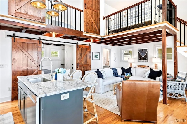 2330 Thornton S, Skaneateles, NY 13152 - kitchen featuring a barn door, a sink, open floor plan, light wood-style floors, and light stone counters