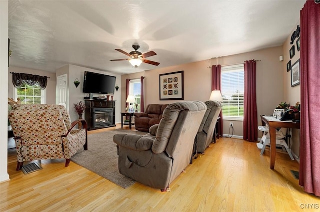 101 Pinehurst Ln, Augusta, NY 13425 - living room with light wood-style flooring, a ceiling fan, a glass covered fireplace, and baseboards