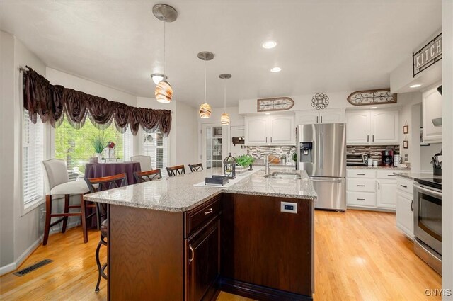 101 Pinehurst Ln, Augusta, NY 13425 - kitchen with appliances with stainless steel finishes, a sink, a breakfast bar area, decorative backsplash, and white cabinetry