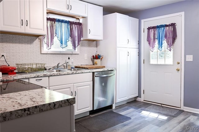 kitchen with stainless steel dishwasher, a sink, tasteful backsplash, and white cabinetry