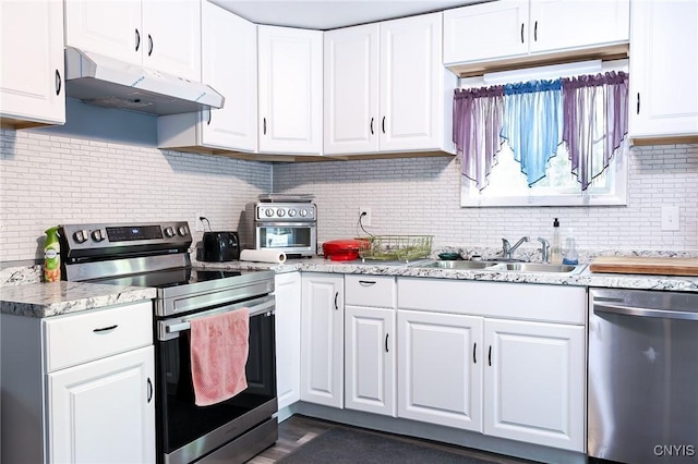 kitchen featuring stainless steel appliances, under cabinet range hood, a sink, backsplash, and white cabinets