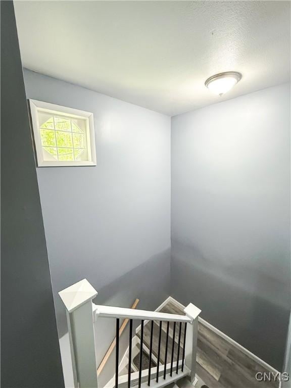 staircase featuring wood finished floors and baseboards