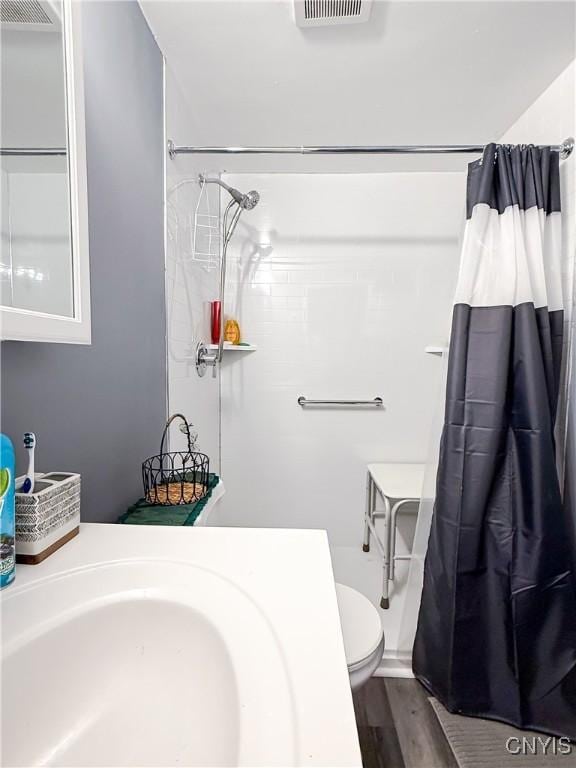 full bathroom with curtained shower, toilet, wood finished floors, and a sink