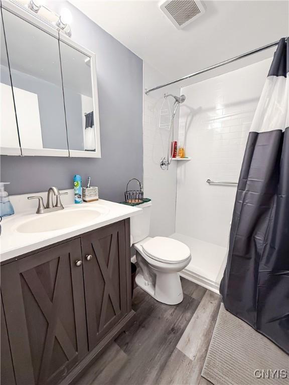 bathroom with wood finished floors, vanity, a shower with curtain, and toilet