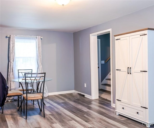 dining room featuring wood finished floors, baseboards, and stairs