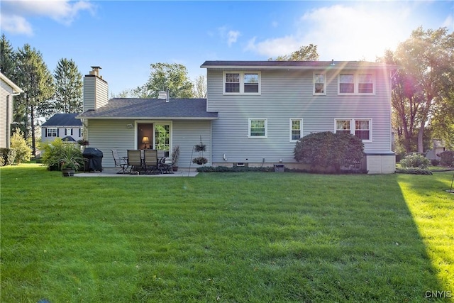 rear view of house featuring a patio, a yard, and a chimney