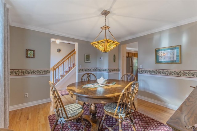 dining room with light wood finished floors, stairs, and crown molding