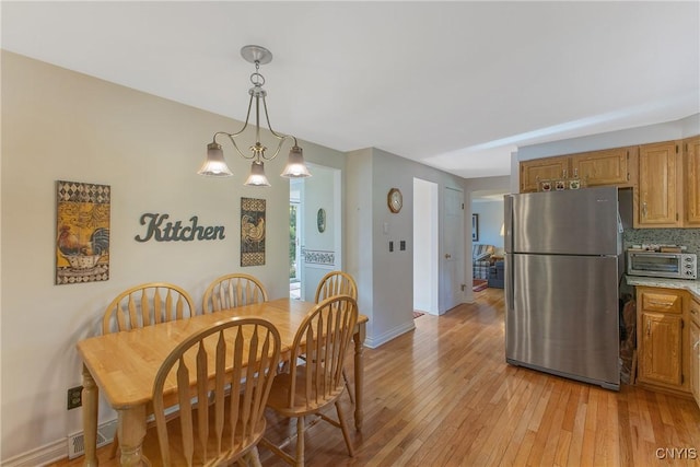 dining room featuring light wood-style flooring, baseboards, and a chandelier