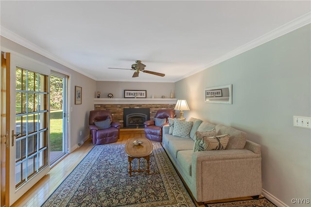 living area with light wood-type flooring, crown molding, a ceiling fan, a fireplace, and baseboards