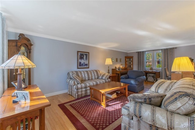 living room featuring light wood finished floors, ornamental molding, and baseboards