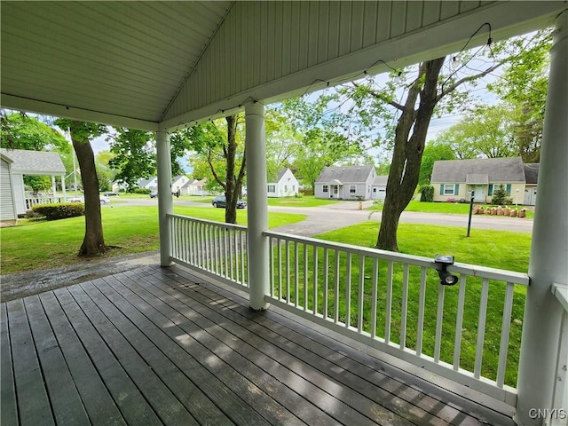 wooden deck with a residential view, covered porch, and a lawn
