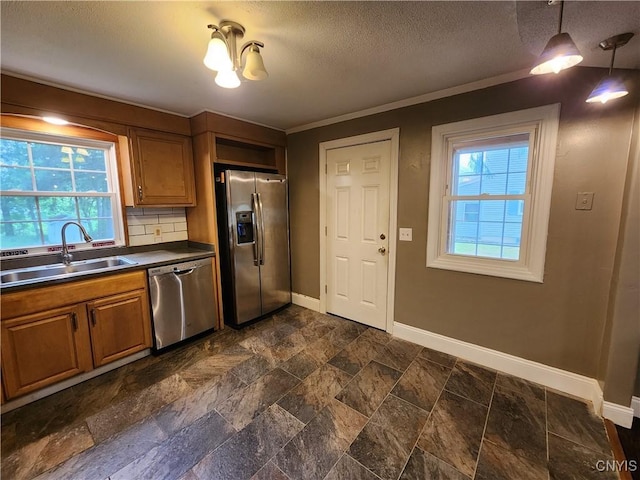 kitchen featuring stainless steel appliances, a sink, dark countertops, baseboards, and dark stone finish flooring