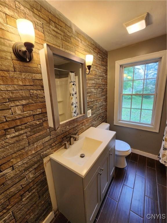 bathroom with toilet, vanity, baseboards, a shower with shower curtain, and wood finished floors